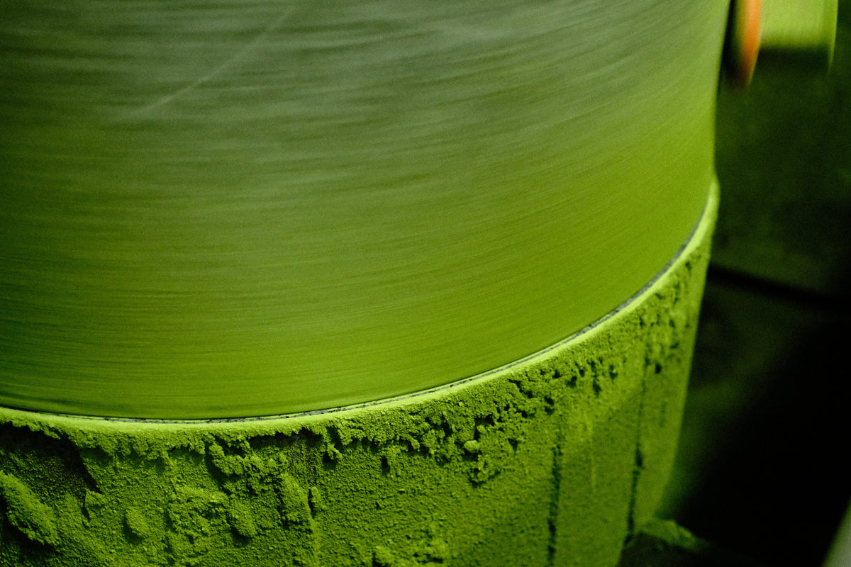 Close-up of a stone mill grinding matcha, coated in fine bright green powder